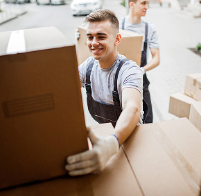 Smiling mover unloading cardboard boxes from a removals van.